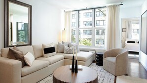A modern living room with a beige sofa, a round coffee table, and a large mirror. - The Diplomat #3 - Boutique Designer Home (New York)
