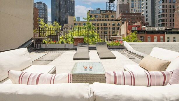 A rooftop terrace with outdoor seating and a table, overlooking a cityscape with tall buildings. - The Diplomat #3 - Boutique Designer Home (New York)