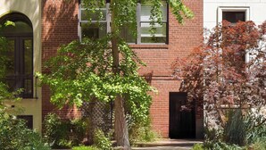 A multi-story building with brick and white facades, multiple windows, and a tree in the foreground. - The Diplomat #3 - Boutique Designer Home (New York)