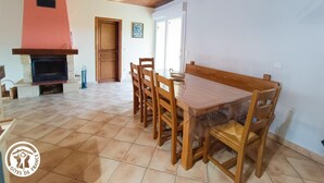 Un comedor con una mesa y sillas de madera, una chimenea y una puerta que da a otra habitación.