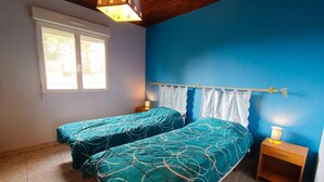 Un dormitorio con dos camas, una ventana y una mesita de noche.