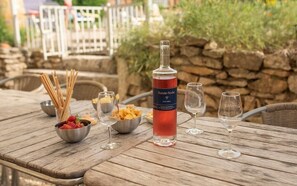 Una mesa de madera con una botella de vino, copas y cuencos de aperitivos.