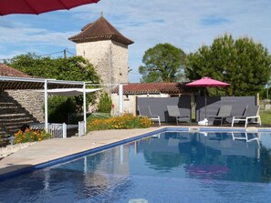 Una piscina con lettini e un gazebo.