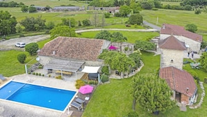 Una extensa propiedad con piscina, un porche cubierto y una torre de piedra.