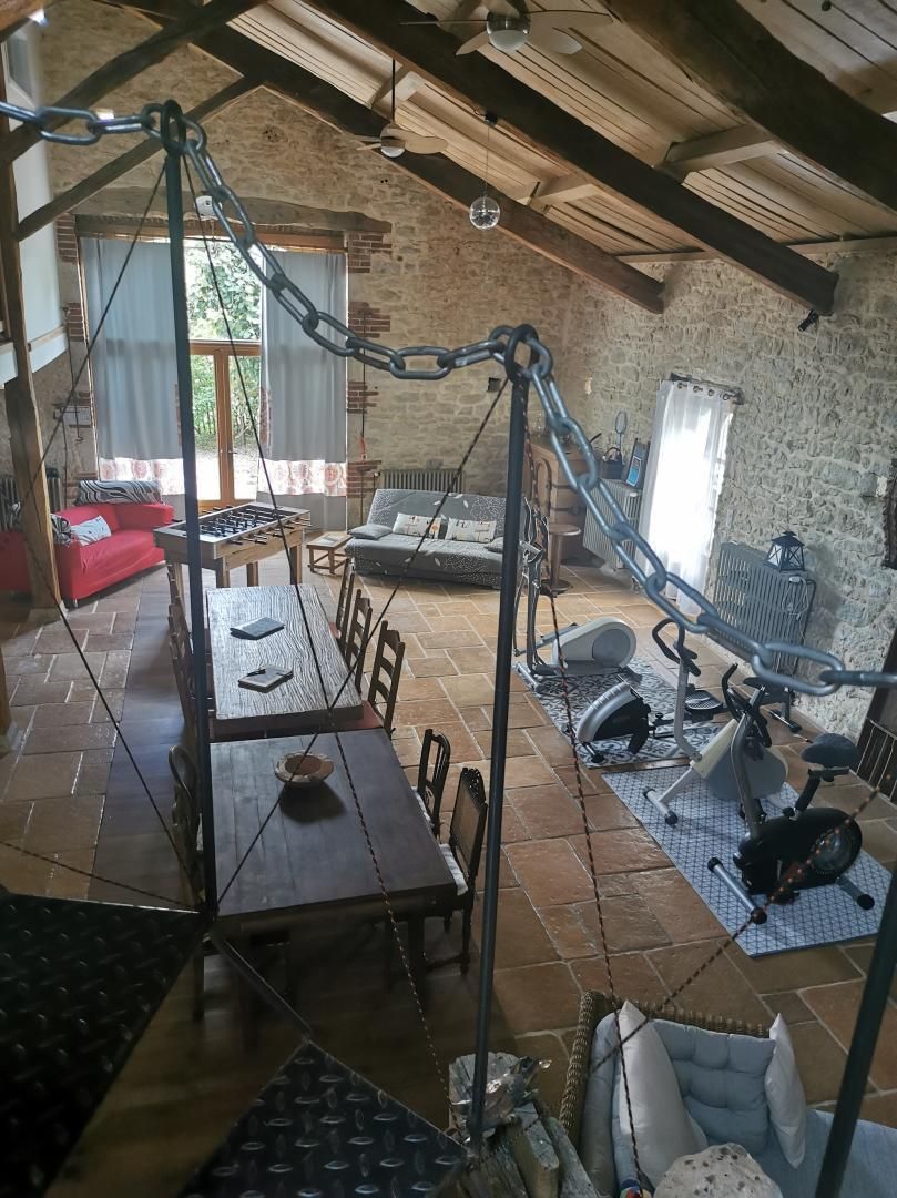 A rustic room with a dining table, sofa, and exercise bike.