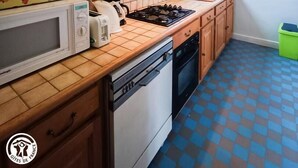 Une cuisine compacte équipée d’un four à micro-ondes, d’un grille-pain, d’une bouilloire et d’une cuisinière à gaz.