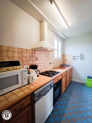 A compact kitchen with a microwave, toaster, kettle, and gas stove. - Gîtes de France® - Le Chataignals (ALBAS)