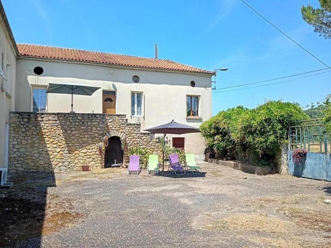 Un bâtiment doté d’une façade en pierre, d’un toit en tuiles et d’une cour pavée avec des chaises longues.