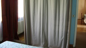 Une pièce avec un lit, une fenêtre avec des rideaux et une porte donnant sur une autre pièce.