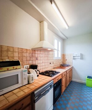 Une cuisine compacte équipée d’un four à micro-ondes, d’un grille-pain, d’une bouilloire et d’une cuisinière à gaz.