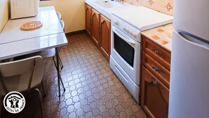 A compact kitchen with wooden cabinets, a white countertop, a built-in oven, and a refrigerator.