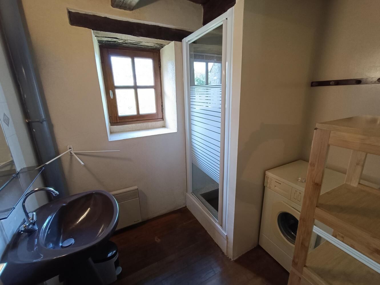 A compact bathroom with a sink, window, and built-in washing machine.