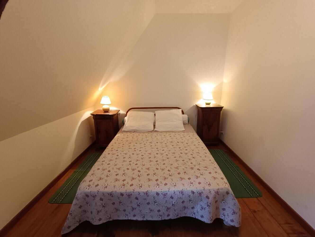 Ein kleines, gemütliches Schlafzimmer mit einem Einzelbett, zwei Nachttischen und einer grünen Matte auf dem Boden.
