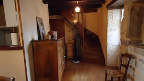 Ein rustikaler Innenraum mit einer Holztreppe, einem Esstisch mit Tischdecke und einem hölzernen Stuhl.
