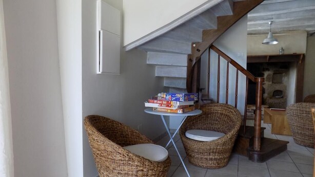 A corner of a room with wicker chairs, a small table with books, and a staircase. - Gîtes de France® - The Presbytery (SENAILLAC-LATRONQUIERE)
