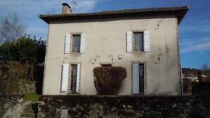 A two-story building with a stone base and a tiled roof. There are four windows with shutters, and a chimney is visible on the roof. - Gîtes de France® - The Presbytery (SENAILLAC-LATRONQUIERE)