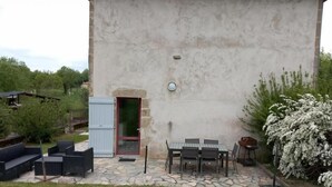 A patio with outdoor furniture, a stone pathway, and a small door leading to a building. - Gîtes de France® - The Presbytery (SENAILLAC-LATRONQUIERE)