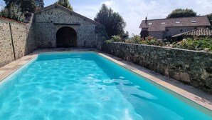 A swimming pool with stone walls and a stone building in the background.