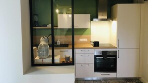 Uma cozinha compacta com armários brancos, forno embutido e micro-ondas.