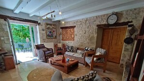 Een gezellige woonkamer met een stenen muur, een houten deur en een eethoek met gestreept beklede stoelen.