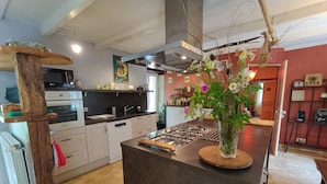 Een moderne keuken met witte kastjes, een centraal kookeiland en een decoratieve vaas met bloemen.
