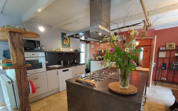 Een moderne keuken met witte kastjes, een centraal kookeiland en een decoratieve vaas met bloemen.