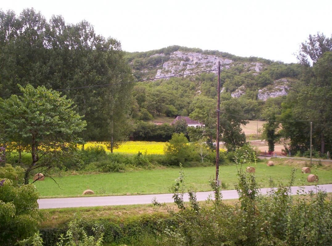 A rural landscape with a road, hay bales, and a house on a hill.