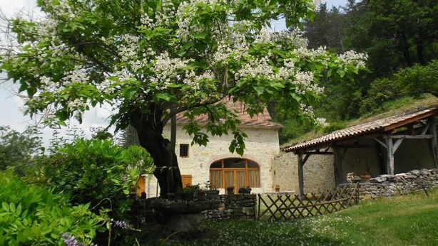 A stone house with a wooden door and a small attached structure. - Gîtes de France® - GITE LAGINESTIERE (CREGOLS)