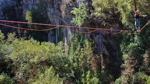 Una persona realizando una acrobacia en una cuerda floja tendida entre dos acantilados.