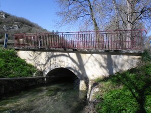 A stone bridge with a metal railing over a small stream. - Gîtes de France® - GITE LAGINESTIERE (CREGOLS)