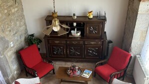 A cozy living area with wicker chairs, a wooden coffee table, and a decorative cabinet. - Gîtes de France® - GITE LAGINESTIERE (CREGOLS)