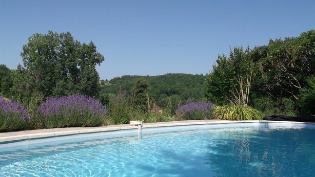 A clear blue swimming pool surrounded by lush greenery and purple flowers. - 46g11622 - Lherm - Gîte (LHERM)