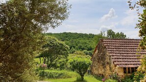 A rustic stone building with a tiled roof, surrounded by lush greenery and trees. - 46g11622 - Lherm - Gîte (LHERM)