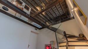 Una habitación con techo alto que presenta paneles de madera elaborados, un techo de cristal y una escalera moderna con barandillas de metal.
