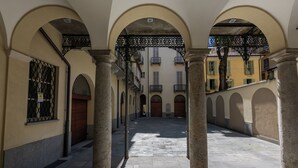 Un callejón estrecho con columnas de piedra y arcos que dan a un edificio con balcones.