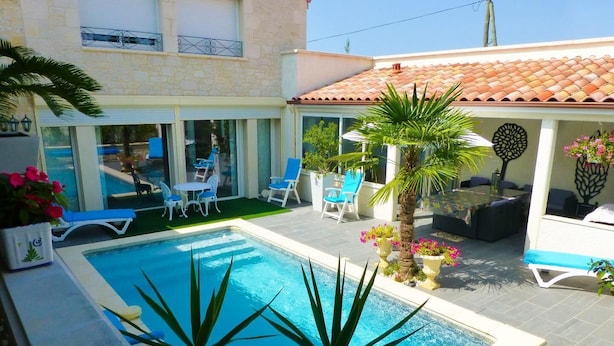 A swimming pool with a patio area, outdoor seating, and potted plants. - Gîtes de France® - LE PATIO DU BARRY (SAINT-VINCENT-RIVE-D'OLT)