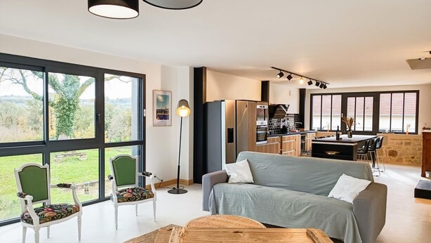 Un salon moderne avec un canapé, une table basse en bois et une vue sur l’extérieur.