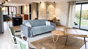 Un salon moderne comprenant un canapé, un coin repas et un mur décoratif en pierre.