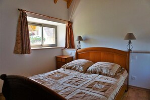 Un dormitorio con una cama de madera, dos lámparas de noche, una mesita de noche y un ventanal con cortinas.