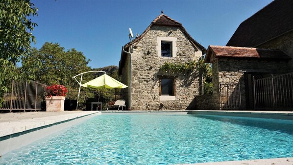 Un edificio de piedra con una piscina delantera.