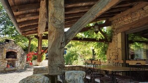An outdoor patio with stone walls, wooden beams, and a stone fireplace.