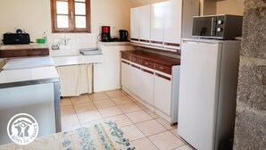 Uma cozinha compacta com armários brancos, forno embutido, micro-ondas e cafeteira.