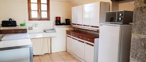 A compact kitchen with white cabinets, a built-in oven, a microwave, and a coffee maker.