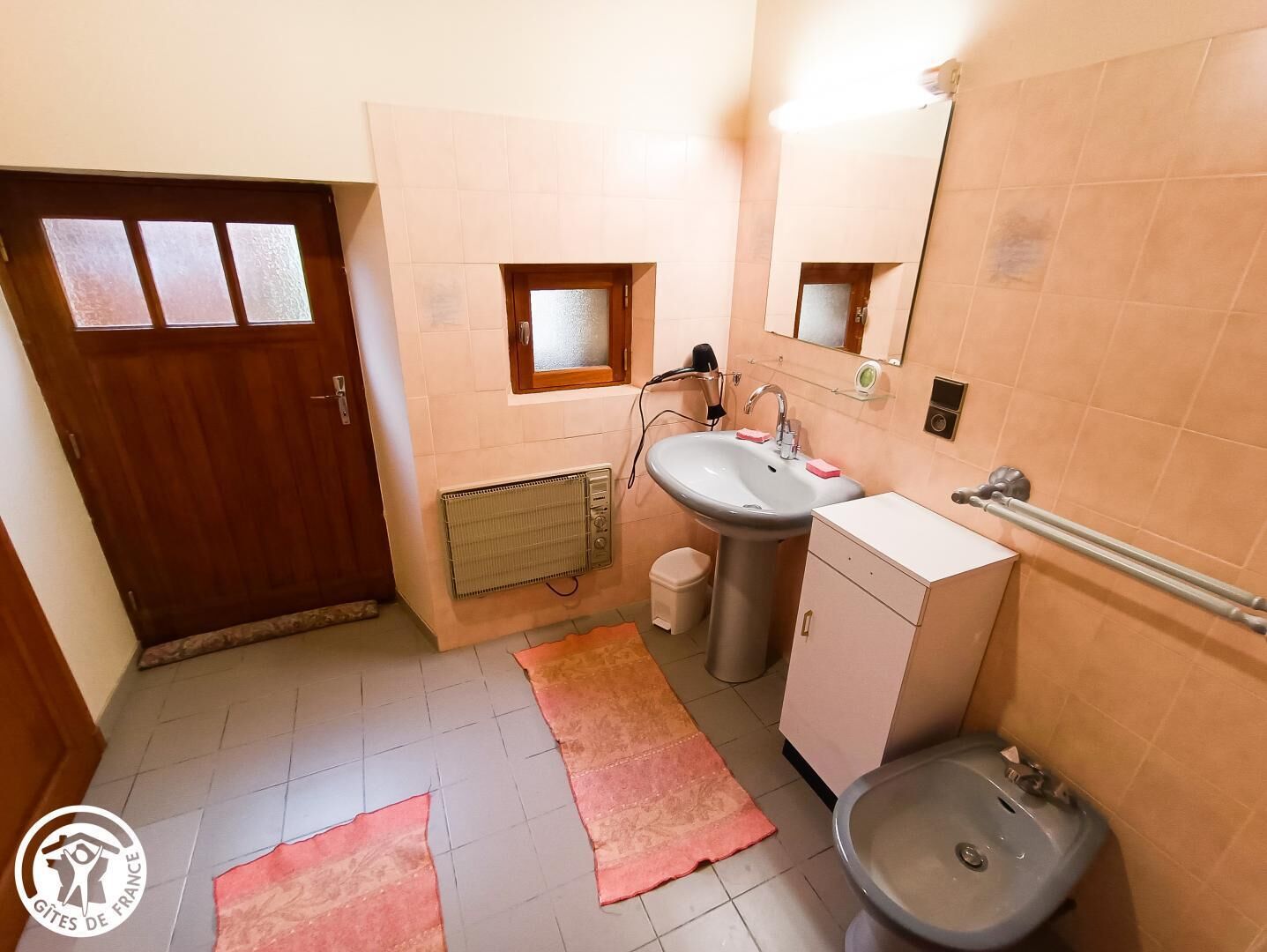 Un baño pequeño con lavamanos, inodoro y un ventanal.