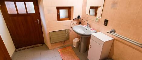 Un baño pequeño con lavamanos, inodoro y un ventanal.