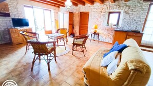 A cozy living area with a sofa, wicker chairs, a small table, and a TV. - Gîtes de France® - La Bergerie (LALBENQUE)