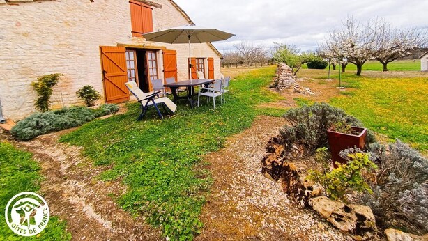 A stone house with a patio, outdoor seating, and a garden. - Gîtes de France® - La Bergerie (LALBENQUE)