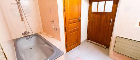 A bathroom with a bathtub, a shower, and a wooden door.