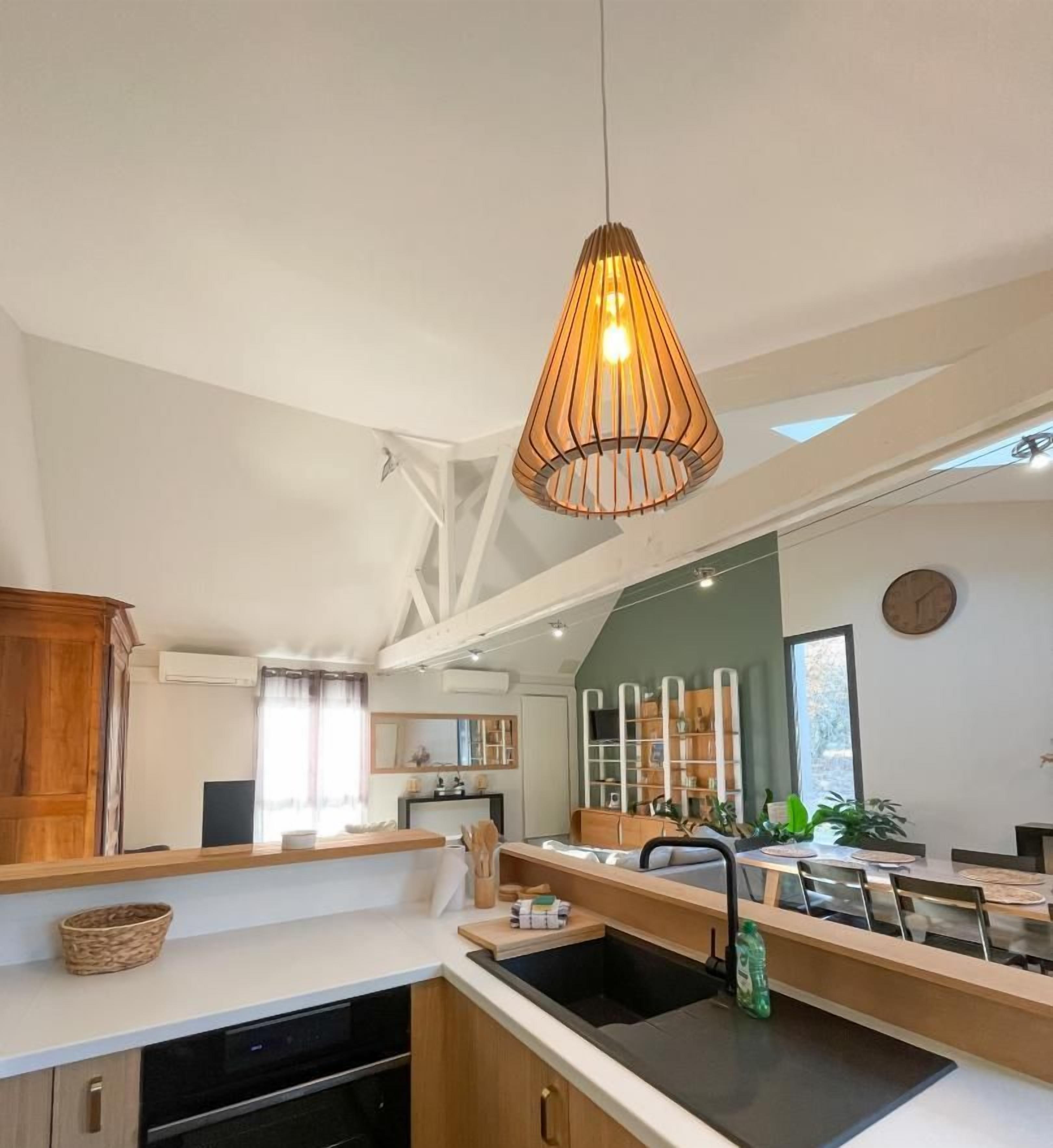 Une cuisine moderne dotée d’un îlot central, de meubles en bois et d’un luminaire suspendu.