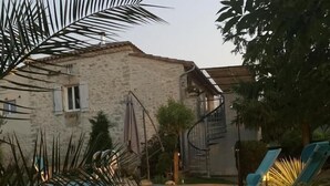 Un pontile in legno con piscina, un edificio in pietra e una palma.